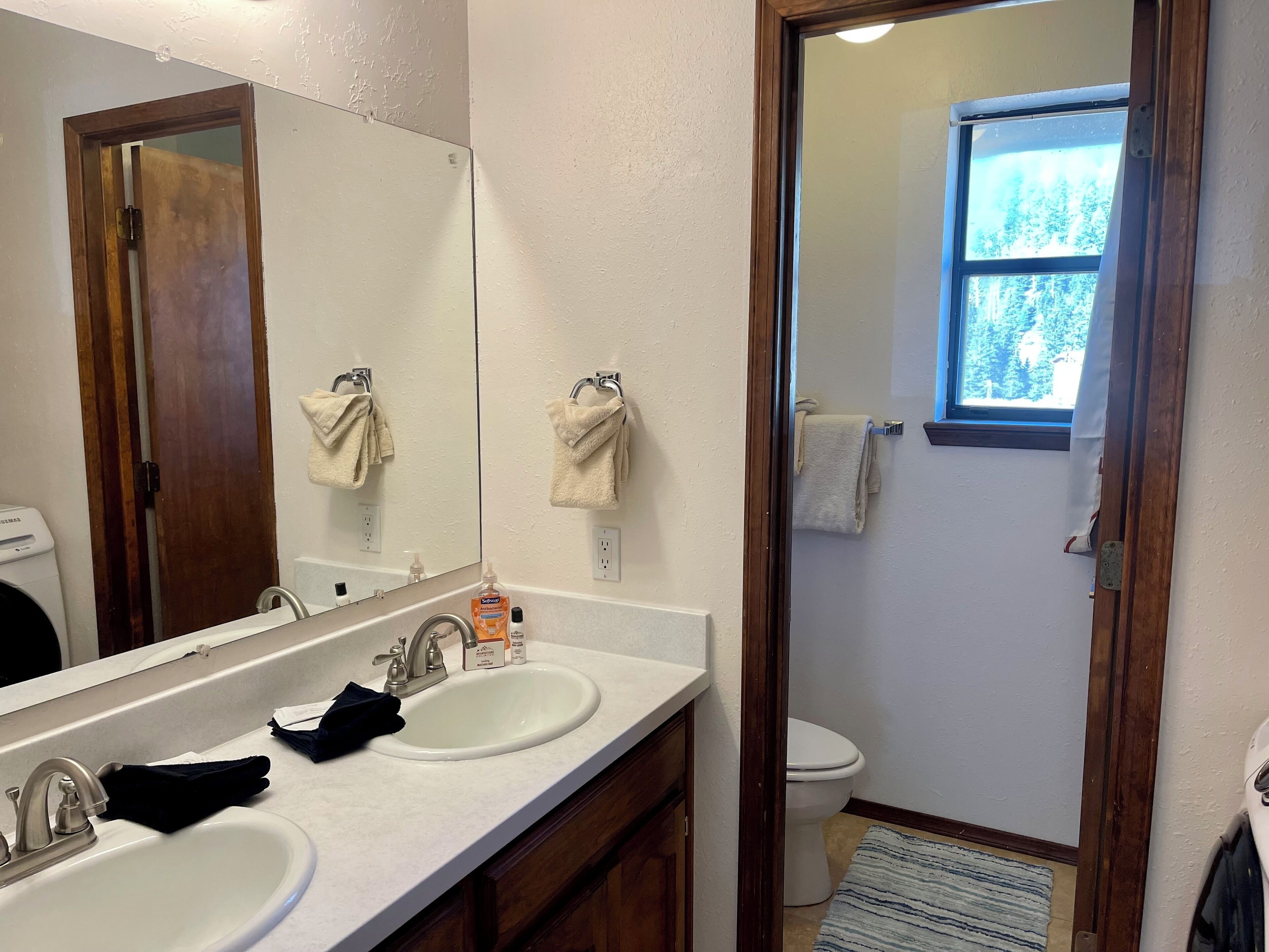 Ein Badezimmer mit zwei Waschbecken, einem Spiegel und einer Toilette.