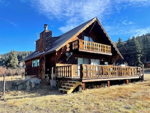 Une cabane en bois dotée d’un balcon, d’une cheminée et d’une terrasse.