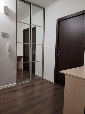 Una habitación con puerta corredera de vidrio, puerta de madera, interruptor de luz y teléfono.