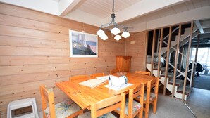 Ein Essbereich mit Holztisch und -stühlen, ein kleiner Hocker und eine Treppe im Hintergrund.