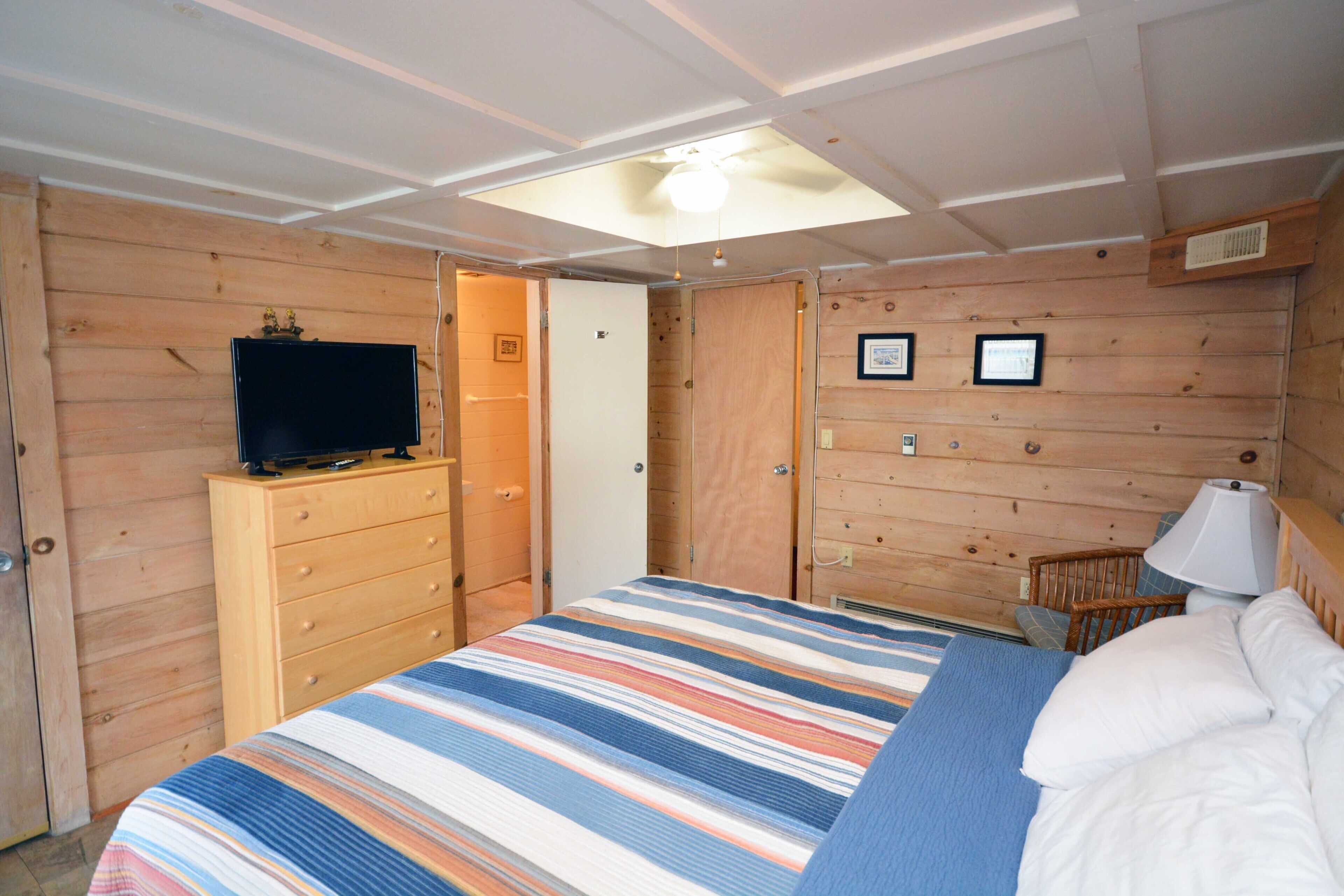 Una habitaci ón con cama, cómoda, televisor y ventilador de techo.
