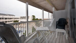 Eine Holzterrasse mit weißen Geländern, einem weißen Tisch und zwei Stühlen.