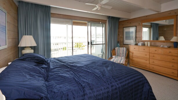 Ein Schlafzimmer mit einem großen Bett, einem Schminktisch, einem Deckenventilator und einem Balkon mit Aussicht.