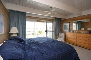 A bedroom with a large bed, a dresser, a chair, a ceiling fan, and a sliding glass door leading to a balcony. - 3 Bedroom Townhouse with Free WiFi, an Outdoor Pool, and Sand for kids to play in located just steps from the beach in midtown! (OCEAN CITY)