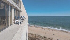 Ein Strandhotel mit Balkon und Meerblick, inklusive Sitzgelegenheiten im Freien und Blick auf den Strand.