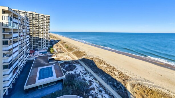 A high-rise hotel with multiple balconies overlooking a beach. - Beautiful 2-bedroom oceanfront condo with gorgeous ocean views, free WiFi, and an outdoor pool located uptown with direct access to the beach! (Ocean City)