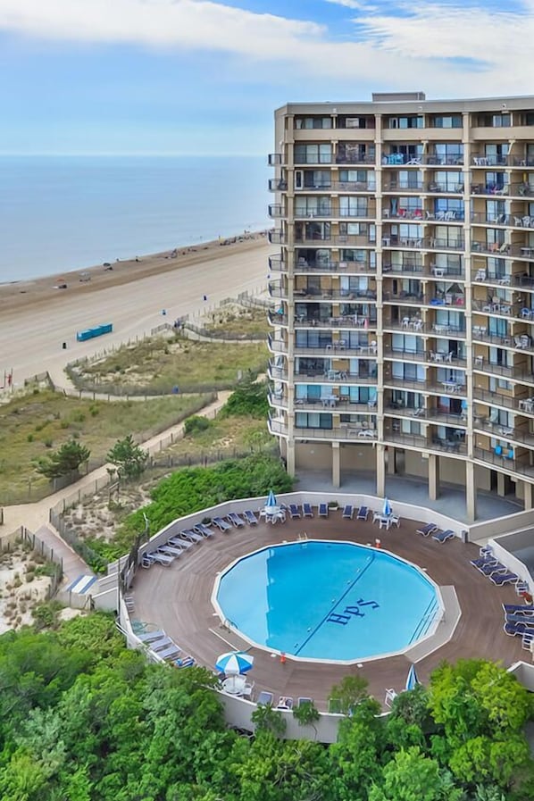 Un hôtel de grande hauteur doté d’une piscine sur le toit, offrant une vue sur la plage et comprenant de nombreux balcons.