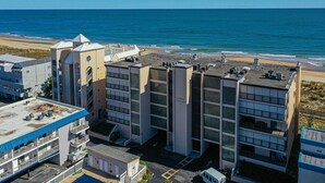 Een hotel met meerdere verdiepingen en een dakterras met uitzicht op het strand.
