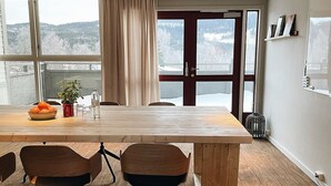 Un salón de conferencias con una mesa de madera, sillas y vistas a un paisaje nevado a través de amplios ventanales.