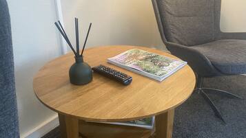 Ett runt träbord med en fjärrkontroll och en tidning.