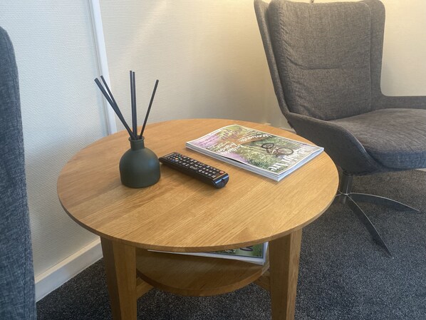 Una mesa redonda de madera con un control remoto y una revista.