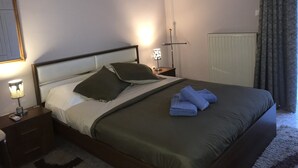 Una cama bien hecha con almohadas, una lámpara de noche y una toalla doblada sobre la cama.