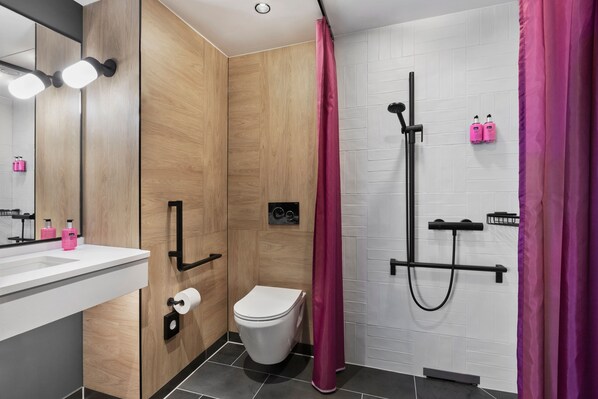 A modern bathroom with a wooden vanity, a toilet, a shower with a black hose, and pink shower curtains. - Moxy Duesseldorf City (Düsseldorf)
