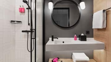 A modern bathroom with a white sink, a round mirror, and a handheld hairdryer on the counter.
