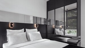 A modern bedroom with a large bed, a bedside table, a mirror, and a window with blinds. - WOL 121 (Odesa)