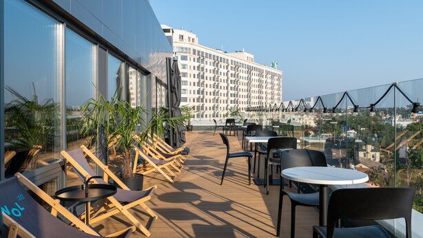 A rooftop terrace with sun loungers, tables, and chairs, overlooking a cityscape. - WOL 121 (Odesa)