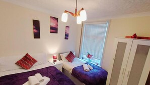 A hotel room with two beds, a wardrobe, a window with blinds, and a ceiling fan. - Garfield Villa-beautiful 4-bed House in Gillingham (Gillingham)