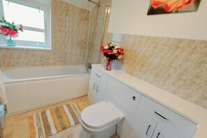 Huis | Badkamer | Een bad/douchecombinatie, een diep bad, een haardroger, handdoeken