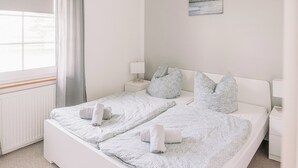 A neatly made bed with rolled towels, a bedside table with a lamp, and a painting on the wall. - Vacation homes island Usedom house Milo 5 -view of the Achterwasser- sauna, whirlpool (Lütow)