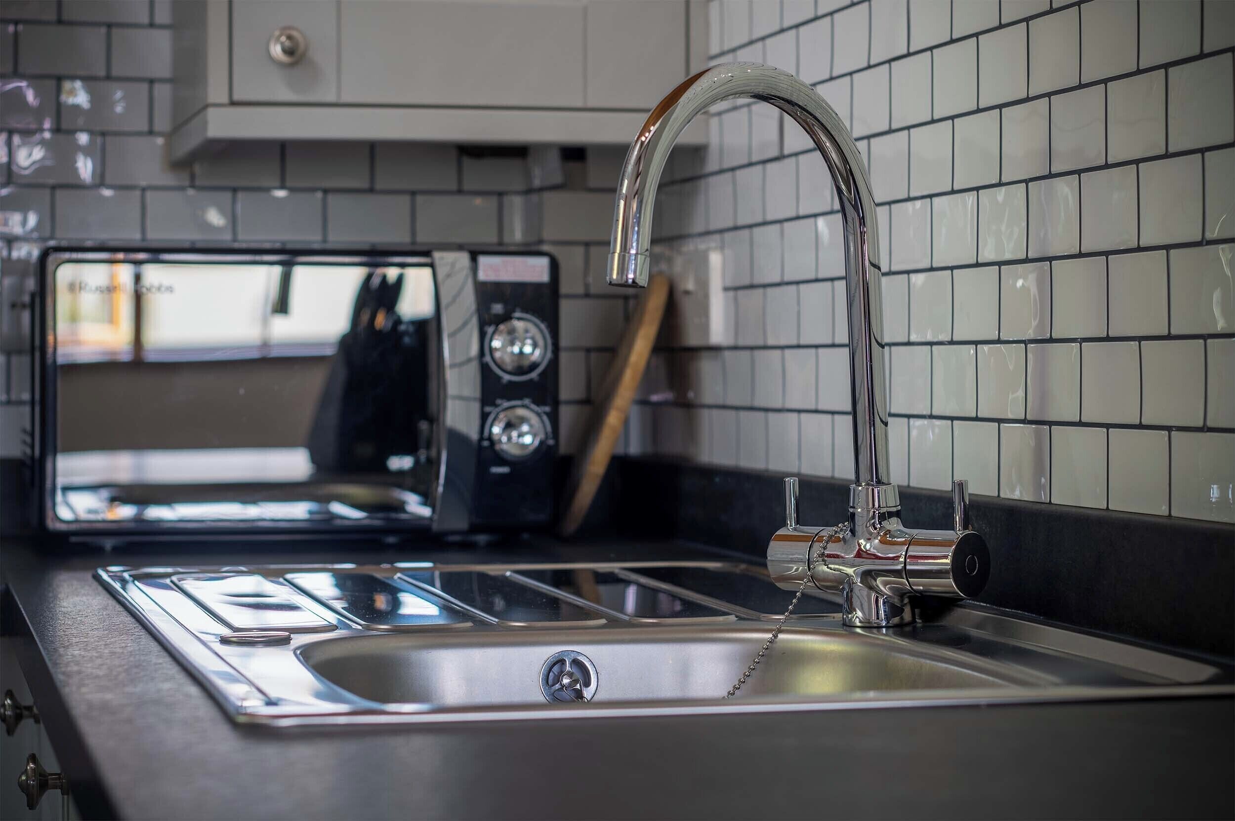 Een keuken met een RVS spoelbak, een moderne kraan en een toaster.
