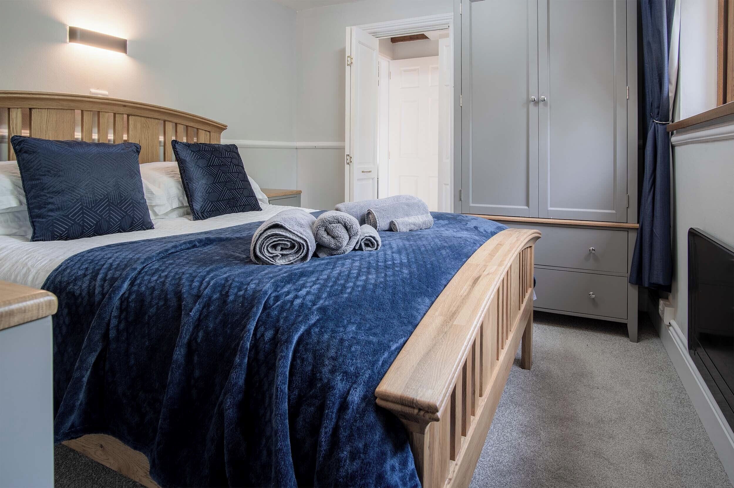 A bedroom with a bed, a wooden headboard, a wardrobe, and a television.