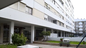 A multi-story building with a flat facade, balconies, and a covered outdoor area with a bench and potted plants. - Centrally located apartment in Triana, Seville+swimming pool (Sevilla)