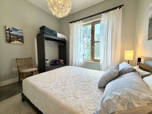 Een slaapkamer met een groot bed, een kledingkast, een stoel en een raam met gordijnen.