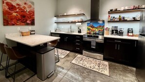 A modern kitchen with a central island, dark cabinetry, and a painting above the stove.
