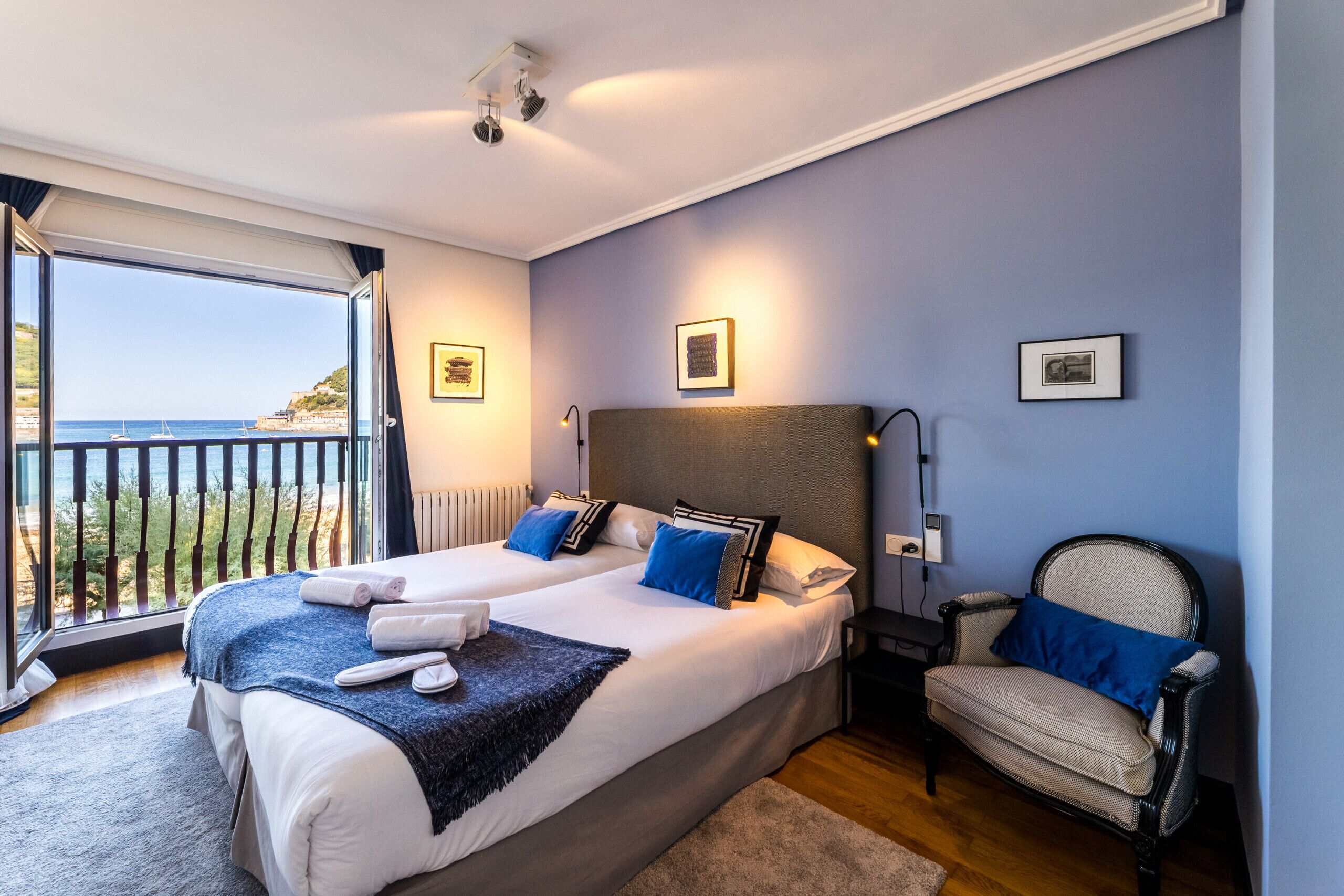 Ein Schlafzimmer mit zwei Betten, einem Nachttisch, einem Stuhl und Meerblick.