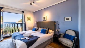 Ein Schlafzimmer mit zwei Betten, einem Nachttisch, einem Stuhl und Meerblick.