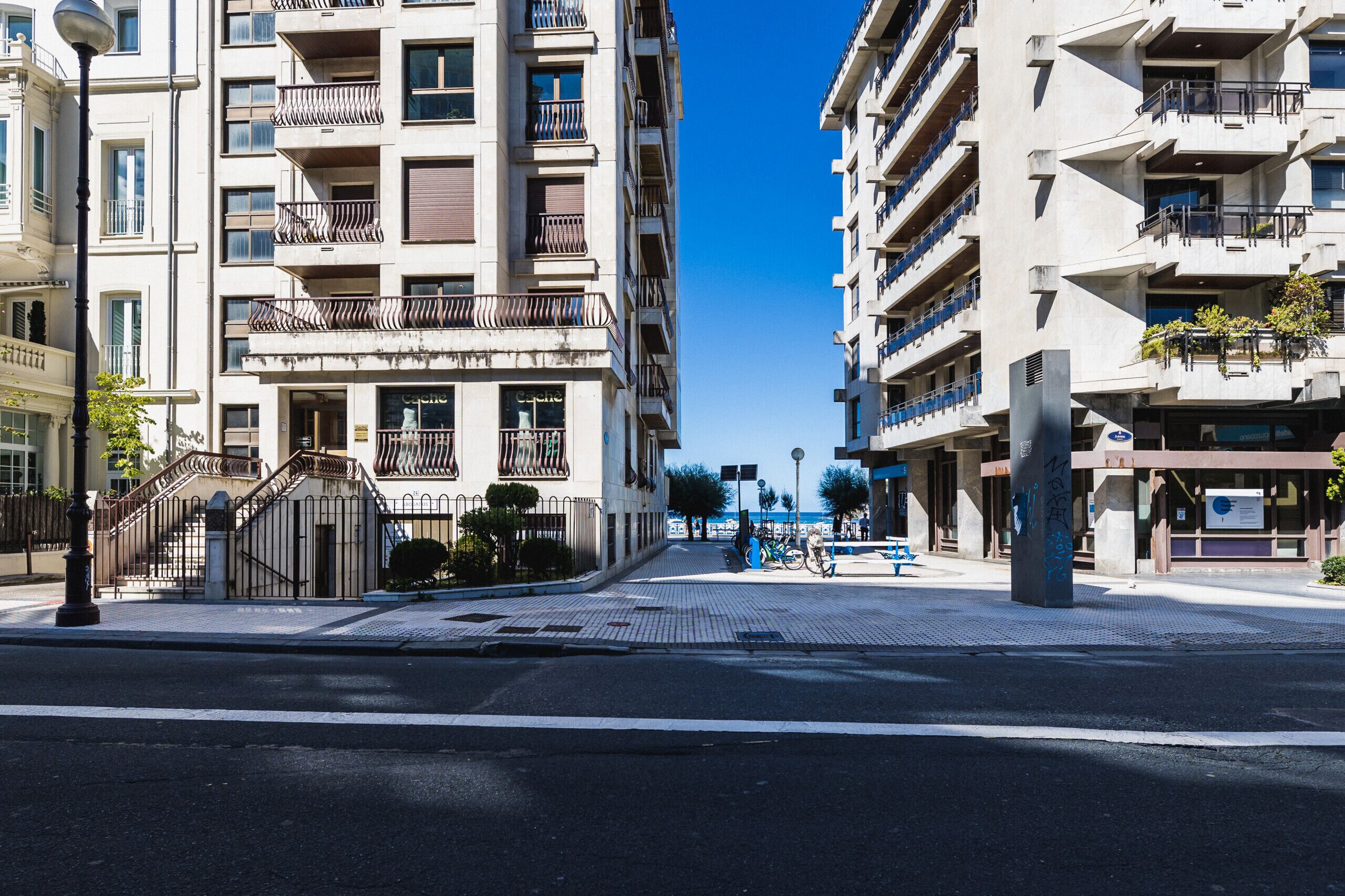 Eine moderne Stadtstraße mit Hochhäusern, blauem Himmel und einer Fußgängerampel.