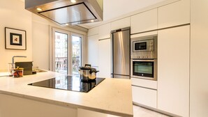 Une cuisine moderne dotée d’un îlot central, d’appareils électroménagers en acier inoxydable et offrant une vue sur la ville par la fenêtre.