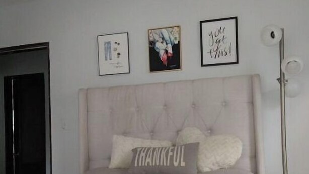Une chambre à coucher avec un lit, une tête de lit et trois tableaux encadrés accrochés au mur.