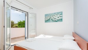 Une chambre à coucher avec un lit, un tableau et une porte-fenêtre coulissante donnant sur un espace extérieur.