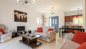 Un salon comprenant un canapé, une table basse et un téléviseur. Il y a également un coin repas avec une table et des chaises.