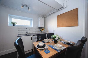 Eine kleine Küche mit Esstisch für vier Personen, einem Fenster und einer Pinnwand.