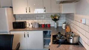 Et moderne køkken med hvide skabe, en mikroovn, elkedel og brødrister.
