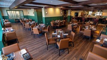 A spacious restaurant with multiple dining areas, wooden floors, and green walls.