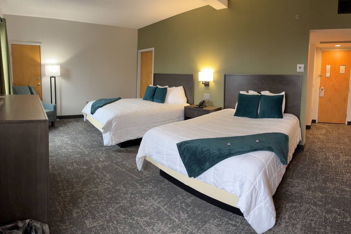 Una habitación de hotel con dos camas, un escritorio y una lámpara.