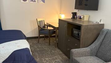 Habitación de hotel con dos camas, un escritorio con silla, televisión y microondas.