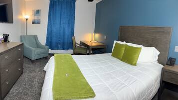 Habitación de hotel con cama, escritorio, silla, cómoda y televisor.
