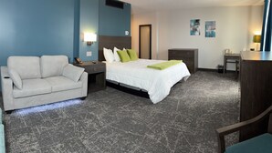 Una habitación de hotel con cama, sofá, escritorio y cómoda.