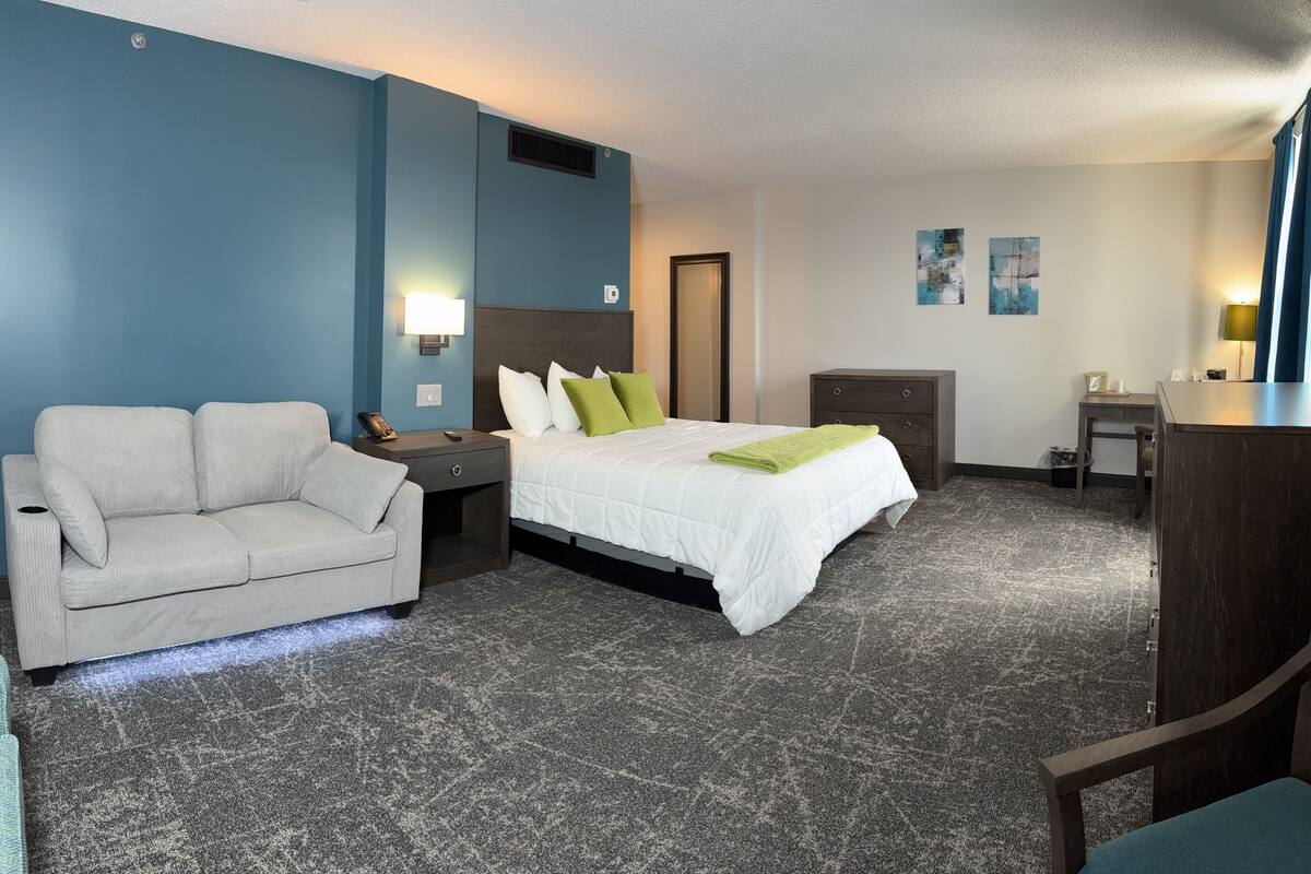 Una habitación de hotel con cama, sofá, escritorio y cómoda.
