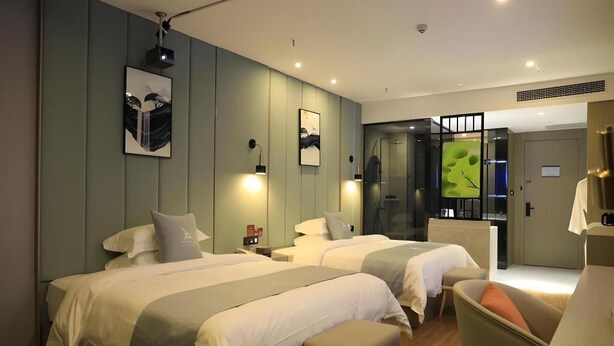 A hotel room with two beds, a desk, and a chair. There are wall-mounted lamps and a door leading to a bathroom. - Greentree Eastern Xinjiang Aksu Airport Hotel (Wensu County)