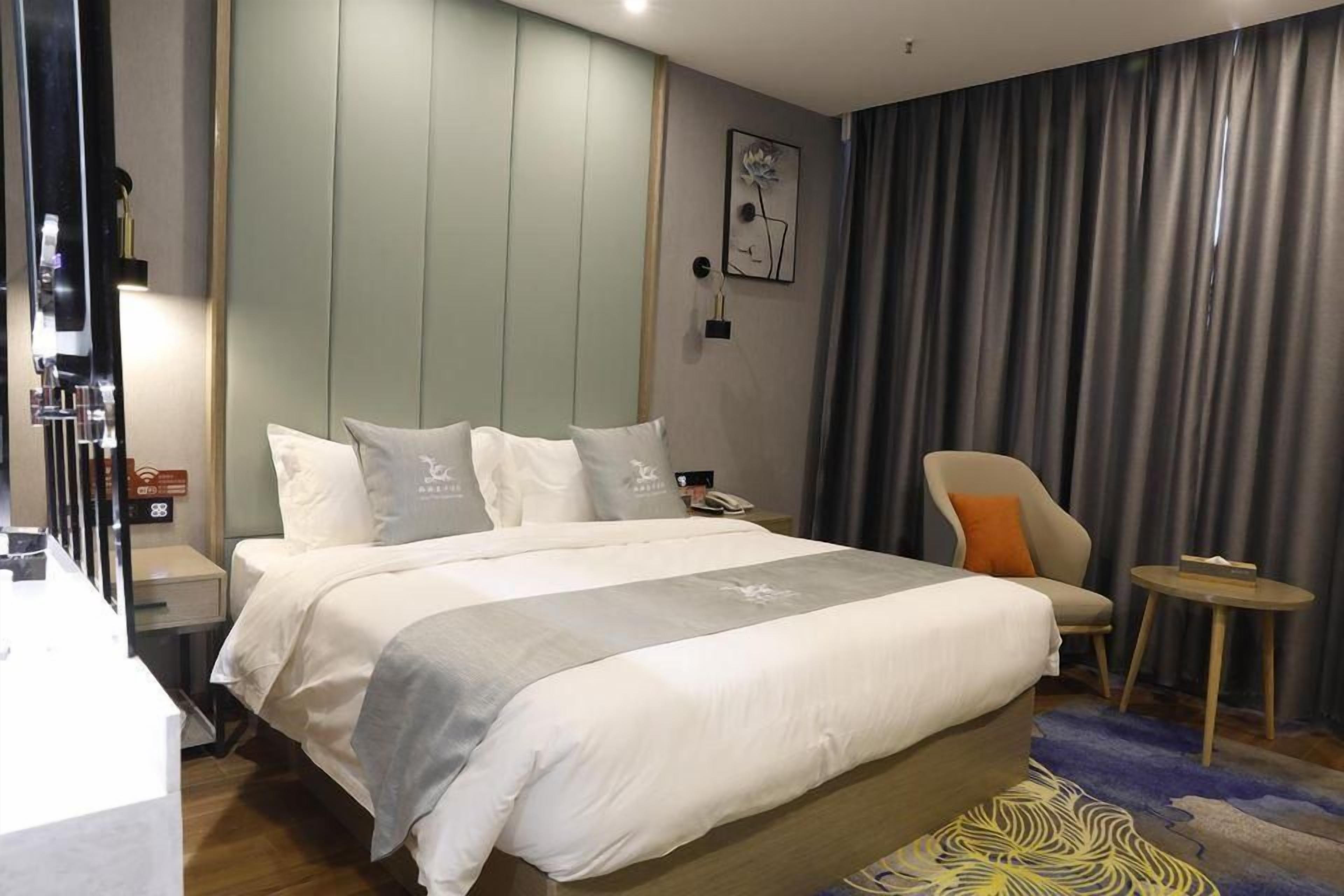 Een hotelkamer met een groot bed, een stoel, een tafeltje en een nachtkastje.
