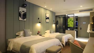 Habitación de hotel con dos camas, un escritorio, una silla y obras de arte en las paredes.