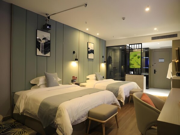 A hotel room with two beds, a desk, a chair, and artwork on the walls.