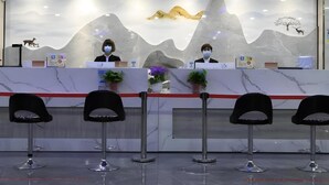 A reception desk with two staff members, a marble counter, and four black chairs in front. - Greentree Eastern Xinjiang Aksu Airport Hotel (Wensu County)