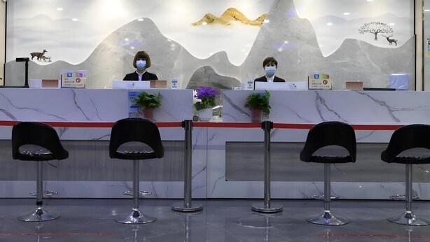 A reception desk with two staff members, a marble counter, and four black chairs in front. - Greentree Eastern Xinjiang Aksu Airport Hotel (Wensu County)