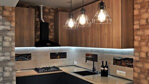 A modern kitchen with a gas stove, black sink, and two pendant lights.